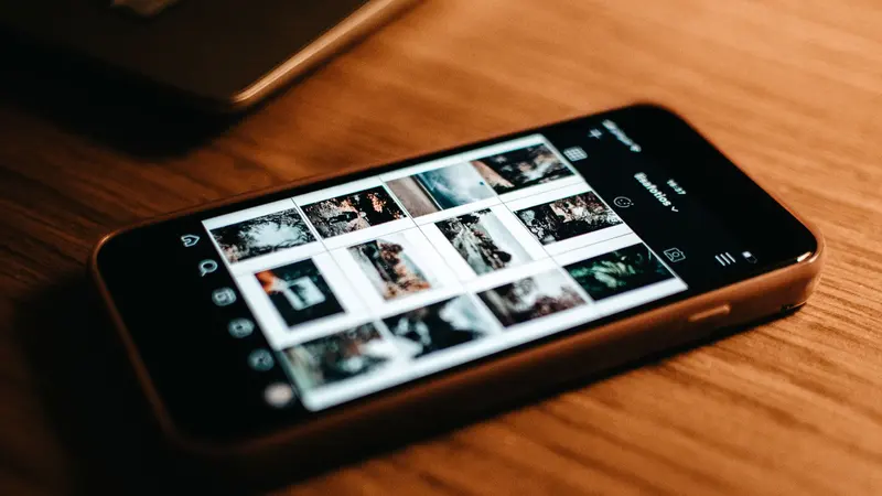 Un smartphone moderne posé sur un bureau en bois affichant une galerie de photos.